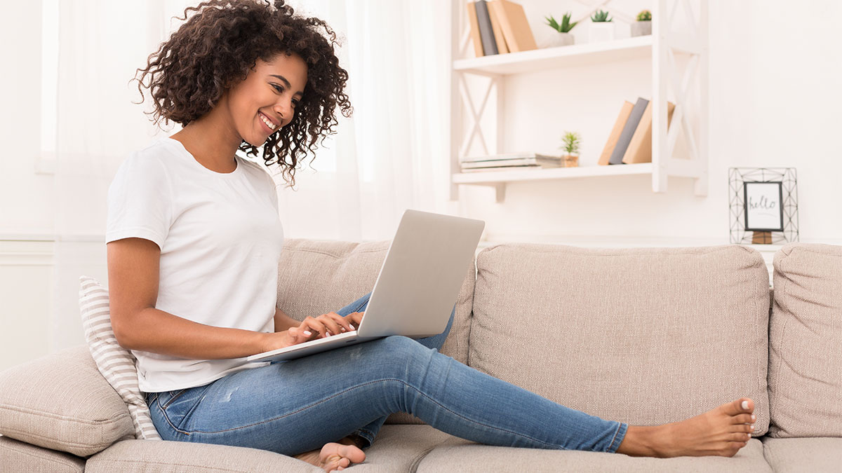 Omnichannel - Smiling woman on couch with laptop