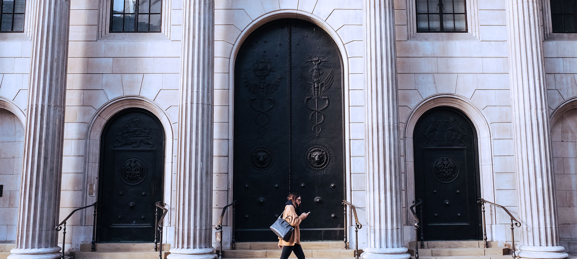 Treasury - Woman walking in front of bank with columns
