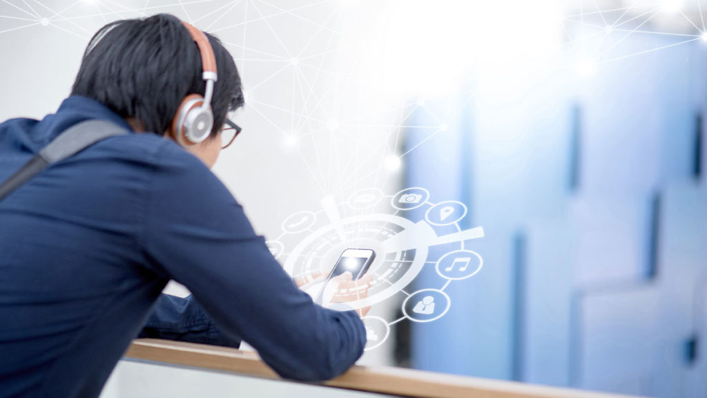 Microservices - student wearing headphones checking his phone