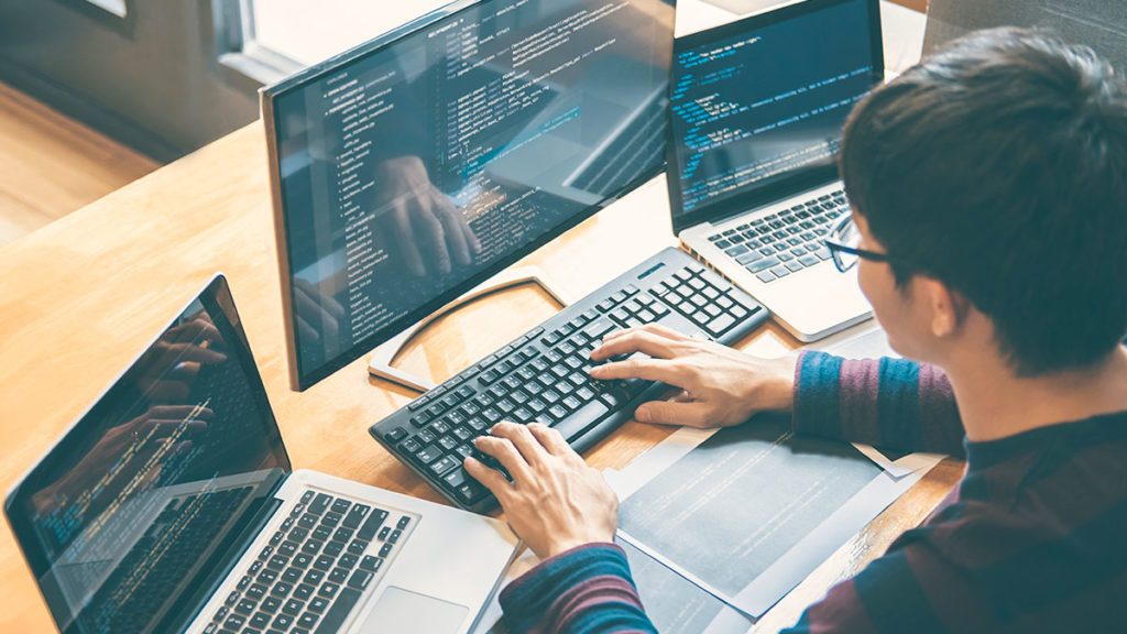 Why Temenos Transact - Man working on multiple screens