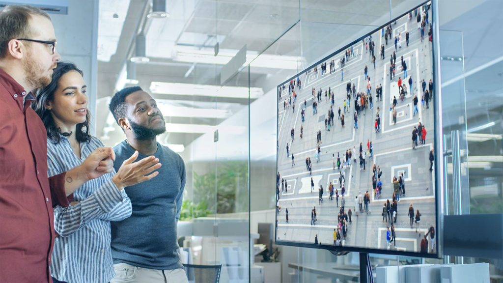 AI and Machine Learning - 3 co-workers in a conference room watching a screen