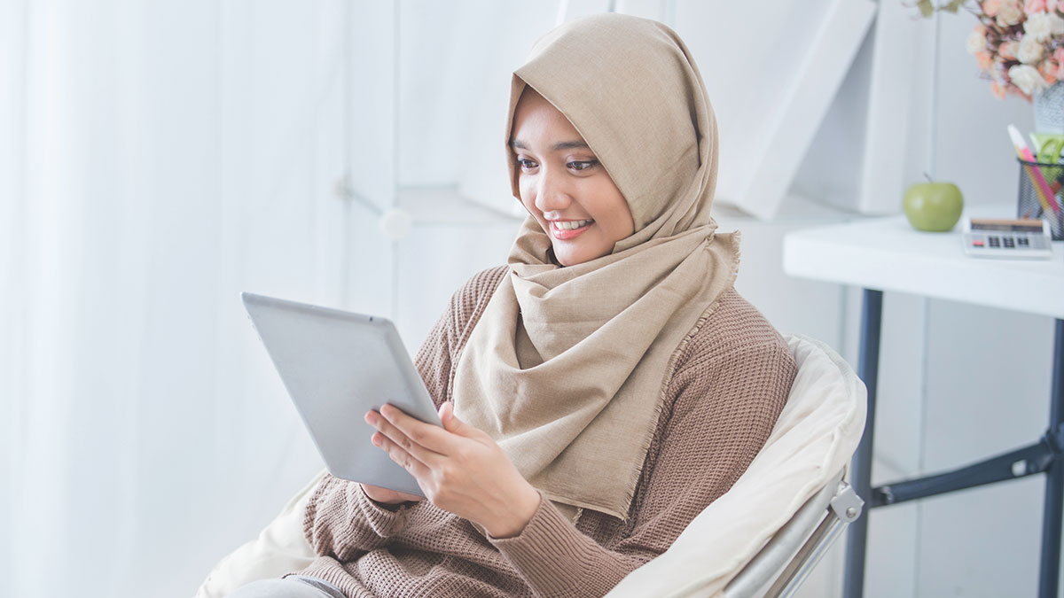 Islamic Banking - Woman wearing hijab using tablet
